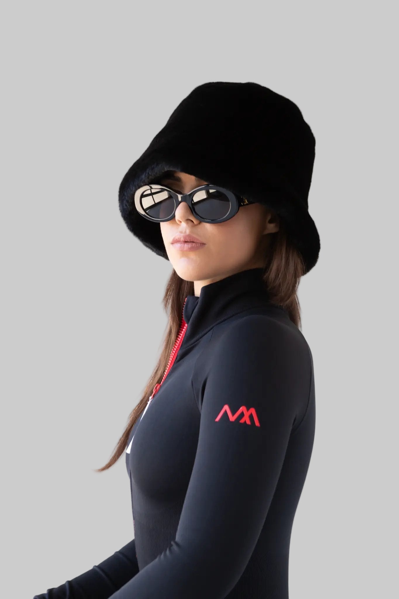 Person wearing a black ski bodysuit with a red logo on a white background