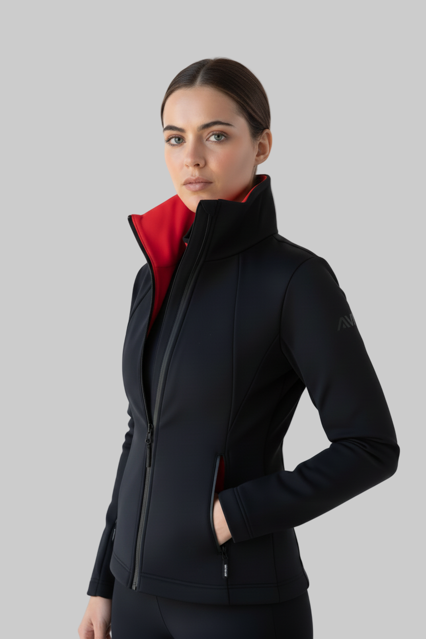Woman wearing a black perfrmance ski jacket with a red lining on a gray background