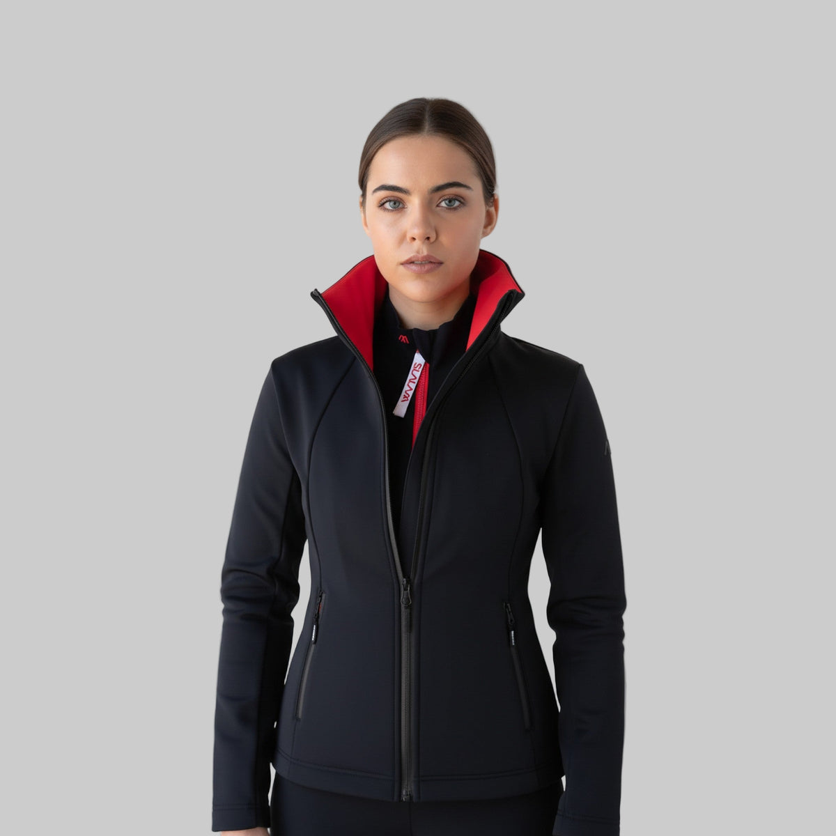 Woman wearing a black performance ski jacket with a red interior on a white background